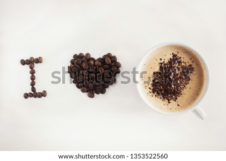 
postcard I love coffee written with coffee beans and a cup of cappuccino frothy and grated chocolate on a beige background in the style of minimalism and the heart of coffee beans