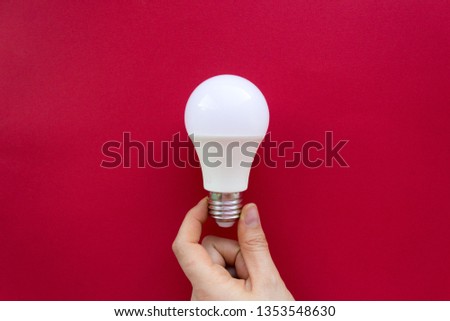 White light bulb in hand on red background. Creative idea, Inspiration, New idea and Innovation concept Royalty-Free Stock Photo #1353548630