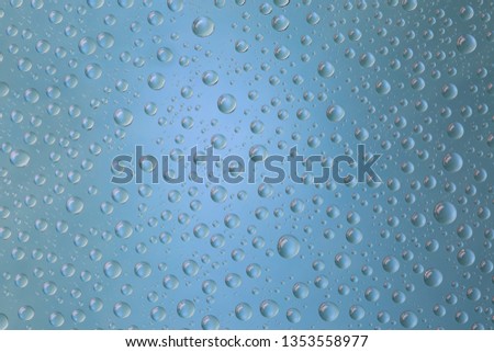 Beautiful water droplets of regular shape on frosted glass with blue light