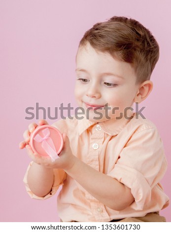 Happy little boy with a gift . Photo isolated on pink background. Smiling boy holds present box. Concept of holidays and birthday.