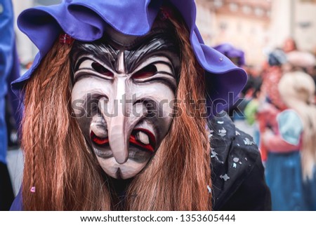 Pretty witch with long nose, violet hat and brown hair. Street Carnival in Southern Germany - Black Forest.