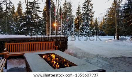 Outdoor Fire Pit in a Snowy Setting At SunriseSunset; VacationTravelCozyFun Royalty-Free Stock Photo #1353607937