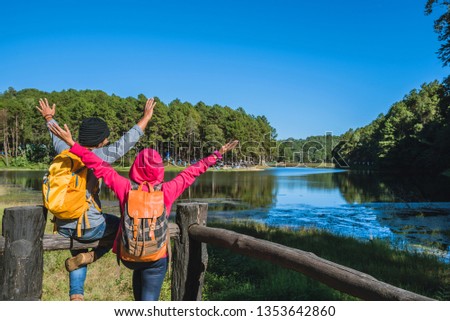 Couples travelers with backpack happy to relax on a holiday,Travel to visit nature landscape the beautiful at lake,  in Thailand.