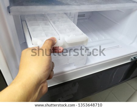 Man hand twisting for ice from the ice maker in new refrigerator.Closed up.