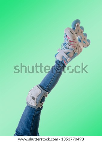 The left leg of the child in roller skates and protective shields on a green background.