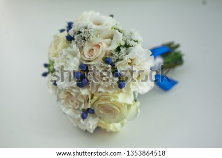 Round bridal bouquet made of natural flowers in white colors with greens and blue berries of hypericum on a white background