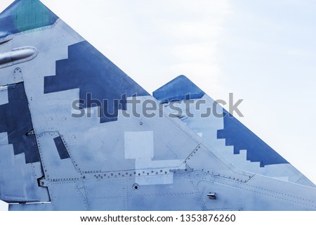 The tail of a military aircraft fighter bomber. Gray and blue pixel camouflage. Coat of arms of Ukraine on the tail of the aircraft.