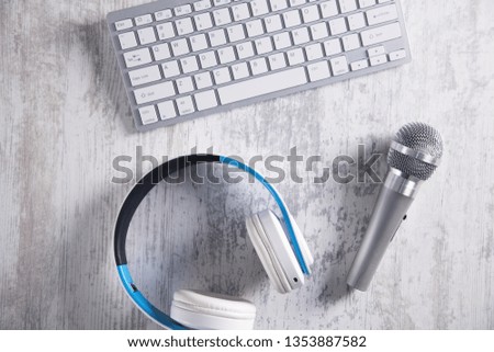 Microphone, keyboard and headphones on a white desk. Top View
