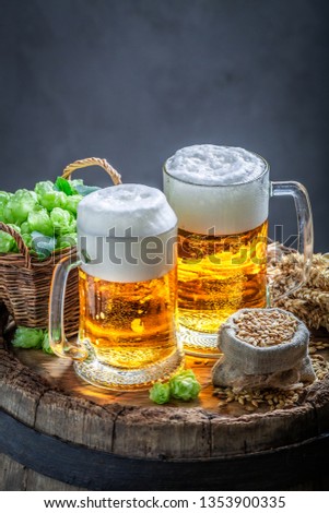 Closeup of beers with foam and hops on old barrel