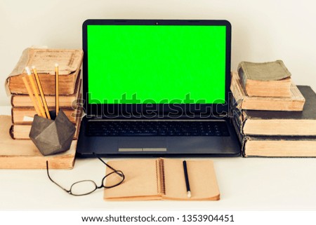 Green screen laptop, stack of old books, notebook education  background. Workplace at home during the pandemic. The quarantine concept of stay home stop coronavirus COVID-19 spreading.