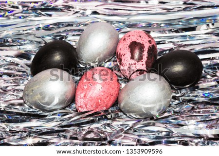Easter eggs. Pink, silver and black colored eggs on a shiny tinsel background. Easter wallpaper. Copy space.