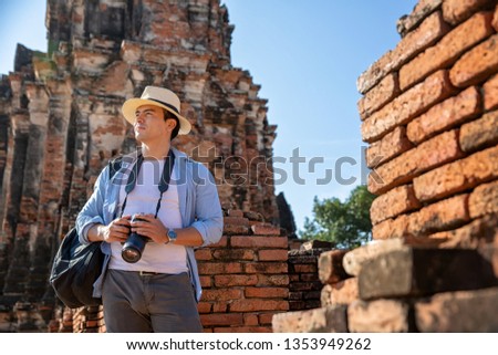 Eastern Asia summer holidays. Caucasian man tourist from back looking at Wat Chaiwatthanaram temple. Travelers take pictures with DSLR cameras. Travel in old city of Ayutthaya, Thailand. Asia tourist.