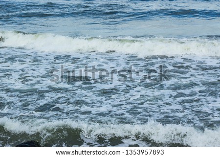 Empty beach, waves and dramatic sky at the Baltic sea shore line