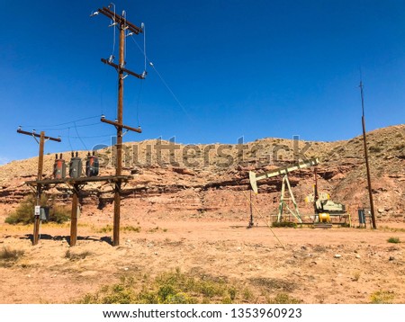 High voltage line, an old oil well in a desert climate. Picture taken on a sunny day.