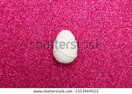 Easter white egg on pink glitter background. Minimal easter concept. Happy Easter card with copy space for text. Top view, flatlay.