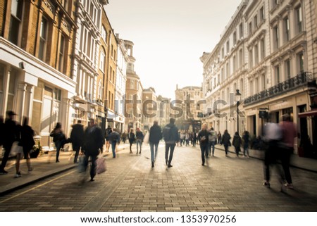 Motion blurred anonymous people on busy city shopping street Royalty-Free Stock Photo #1353970256