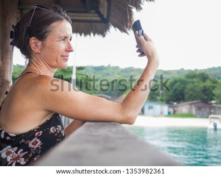 Portrait of a relaxed caucasian woman in Thailand making a selfie with the mobile phone. Tropical summer travel vacation.