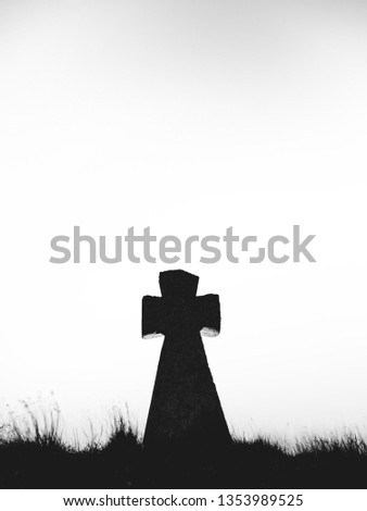 dramatic black tomb cross under white sky