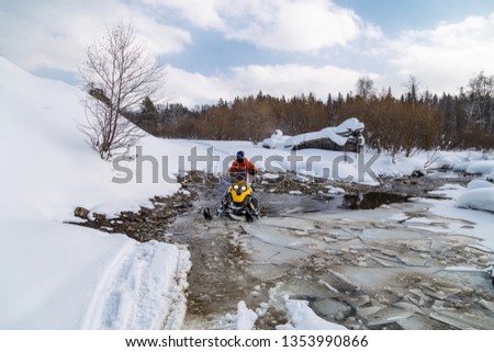 Athlete on a snowmobile forwarded across the river in the mountains of the Urals.