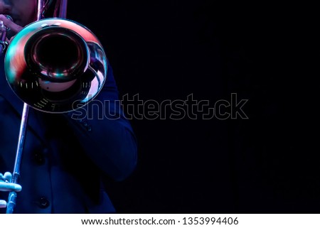 a man hands playing on a trombone black background Royalty-Free Stock Photo #1353994406