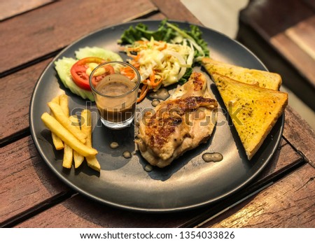 Chicken steak with french fries, bread and vegetable.