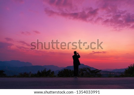 Man taking photos of sunset with mobile phone 