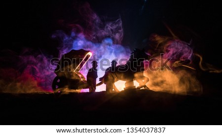 Artwork decoration. Silhouette of old coach with horse on dark toned foggy background. Selective focus