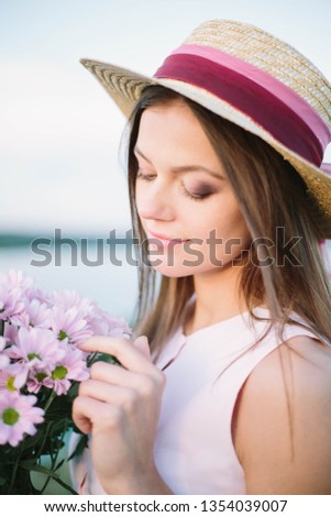 girl with flowers and a hat near the river