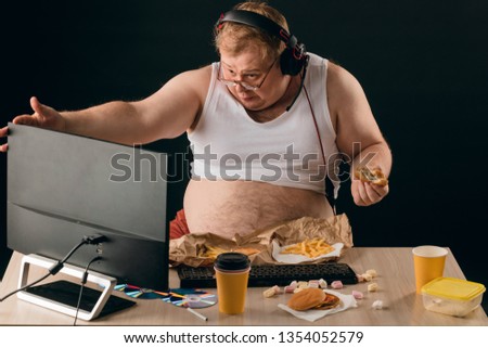 Obese man talking with a computer. close up portrait. isolated black background.lifestyle concept. pastime