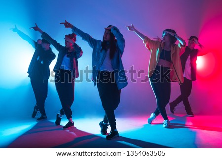 Animation group of young women and men dancing over red and blue dual color light on dark background