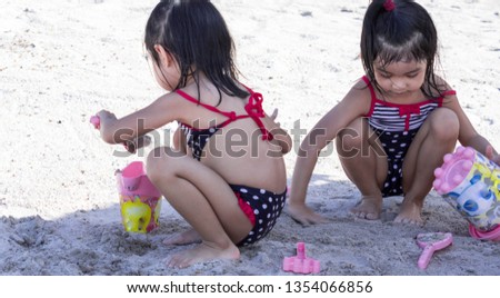 cute asian female toddler twins while playing on sand in a beach resort in asia