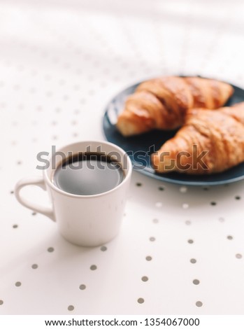 Coffee cup and fresh baked french croissants in blue plate on white background. Breakfast.