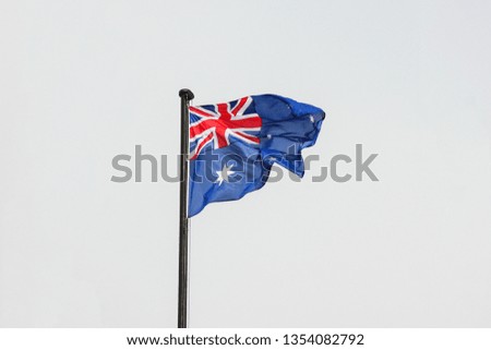 Flag of Australia on flagpole against the overcast blue sky