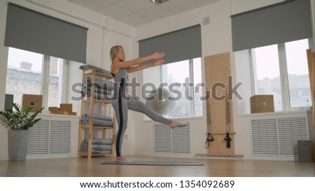 trainer shows pilates exercisesPortrait of best enduring beautiful strong model sporty slim lady wearing sports top and panties showing demonstrating arms muscules at pilates power class