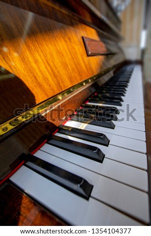 Wide angle vertical view of piano keys lit by sunlight. Piano keyboard with selective focus. Diagonal view. Piano keyboard perspective. Music instruments series
