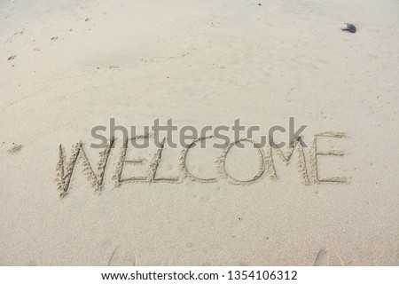 The word “welcome” was written on the sand at the beach. 