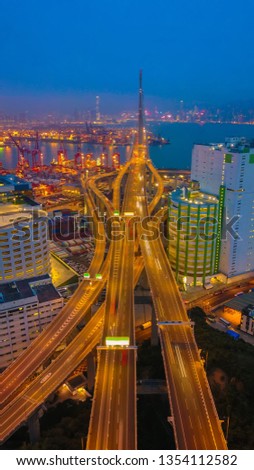 Aerial bird eye view Photography viewpoint traffic Container Cargo freight ship with working crane bridge in shipyard under Stonecutters highway bridge at twilight for Logistic Import Export Hong Kong