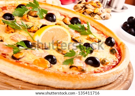 Delicious pizza with seafood on wooden stand