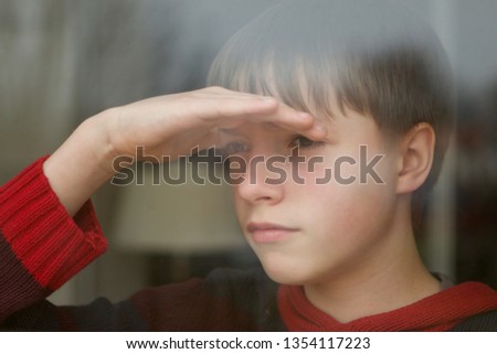 Caucasian teenage boy looking through a window deep in thought