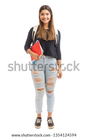 University learner holding books and smiling in casuals against plain background