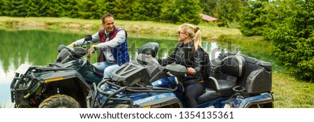 Young couple having fun on mountain while driving a quad bike on a summer day. Young man and woman on an ATV.