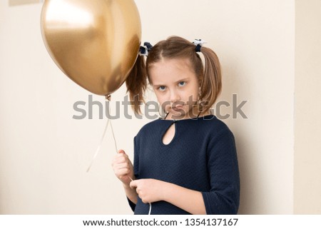 little girl stands with a golden balloon