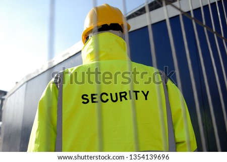 Security guard behind metal fence. 