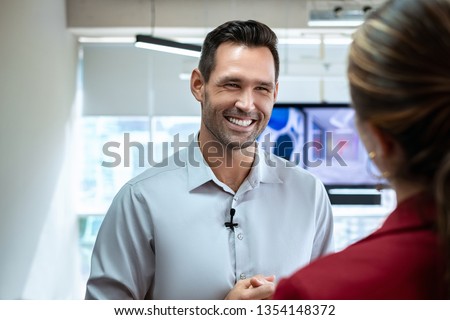Happy businessman during corporate interview with female journalist. Manager answering question in office. Young woman at work as reporter interviewing business man during presentation