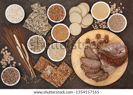 High fibre super food with whole wheat pasta, whole grain walnut and rye bread, crackers, seeds, nuts, grains, oatmeal, oats, barley and bran flakes with wheat sheath on lokta paper background. Royalty-Free Stock Photo #1354157165
