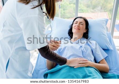 Doctor is holding a handle on the patient's stomach. She has severe pain. Cause of abdominal pain. It is a painful menstrual period or bladder. And ectopic pregnancy. Immediate treatment immediately. Royalty-Free Stock Photo #1354167983