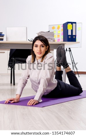 Young female employee doing exercises at workplace 