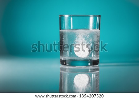 Dissolving  an effervescent tablet in a glass of water at blue background with copy space