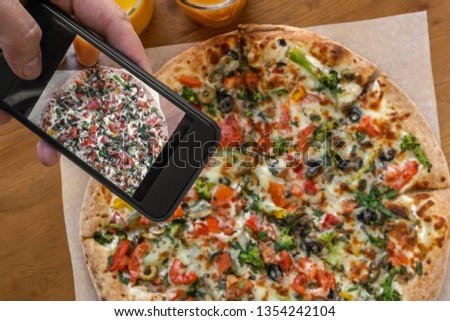 A man takes a photo of a pizza on a smartphone for social networks.          