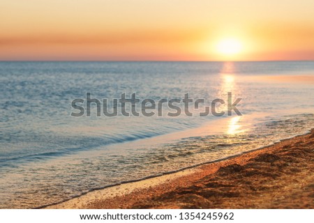 Beautiful sunset over a calm ocean or sea. Bright sunset against the sky and the sea. Sunset on the beach. 